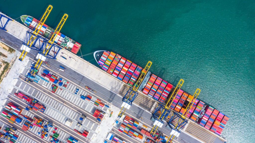 Aerial view of colorful shipping containers at a busy port docked by container ships.