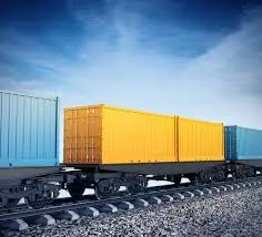 Freight train carrying colorful cargo containers on tracks under a blue sky.