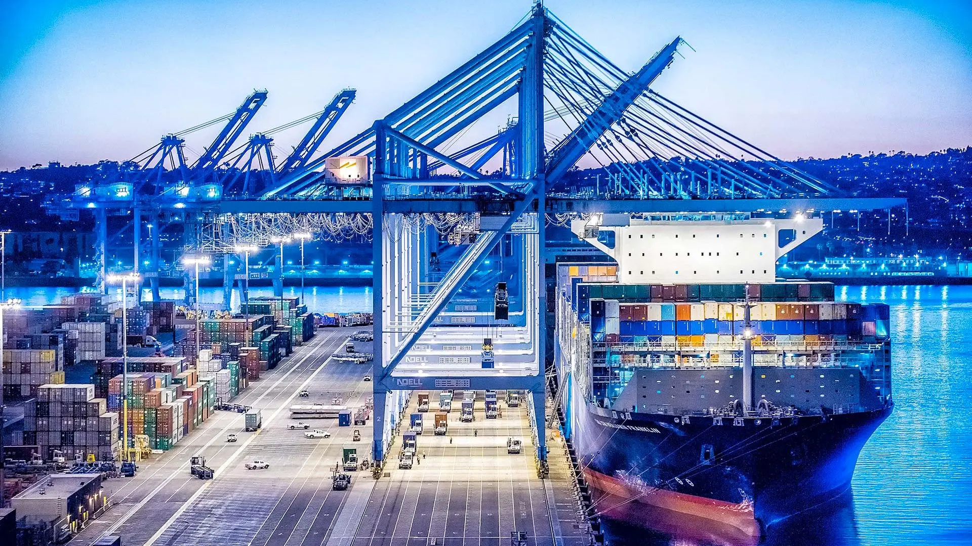 Cargo ship docked at a busy port with cranes unloading containers.